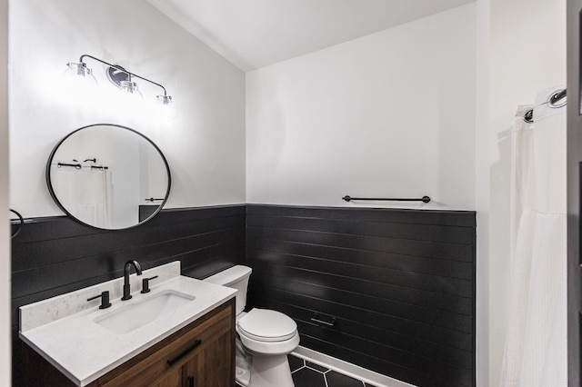 bathroom with tile walls, vanity, tile patterned floors, and toilet