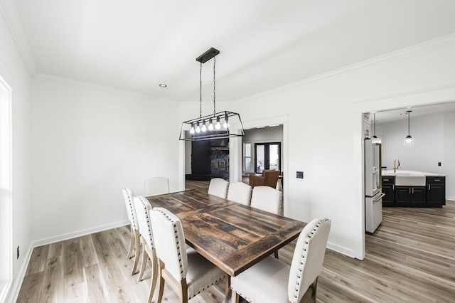 dining space with sink, light wood-type flooring, and crown molding