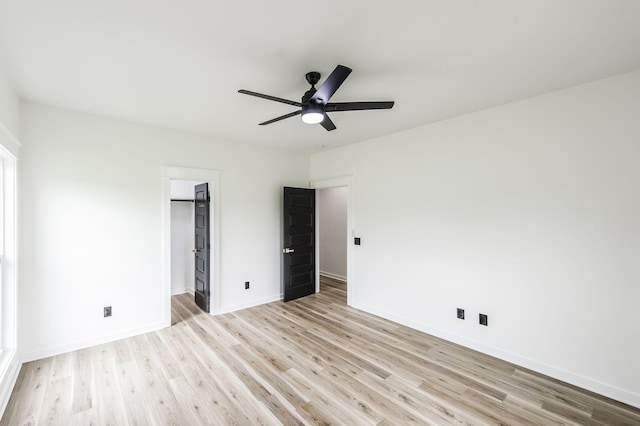 unfurnished bedroom featuring ceiling fan, a spacious closet, and light hardwood / wood-style floors