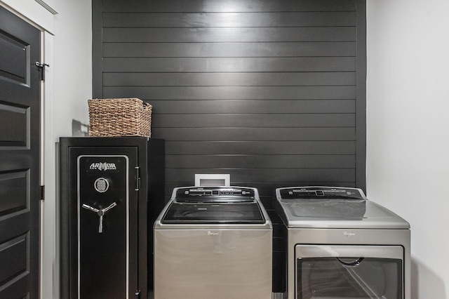 clothes washing area with washer and dryer and wooden walls