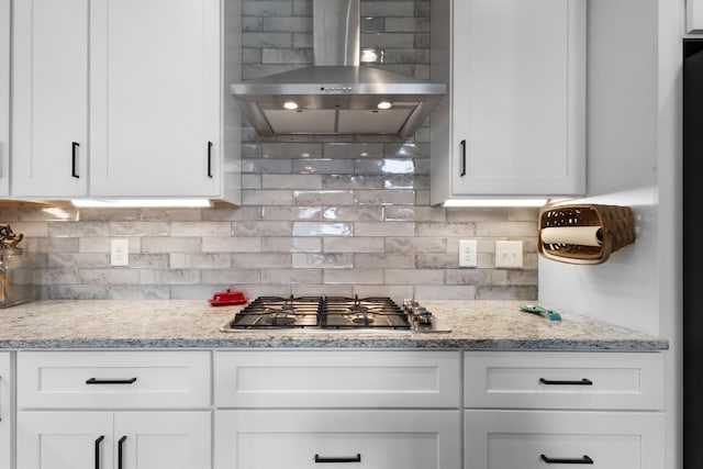 kitchen with white cabinets, tasteful backsplash, stainless steel gas stovetop, and wall chimney exhaust hood