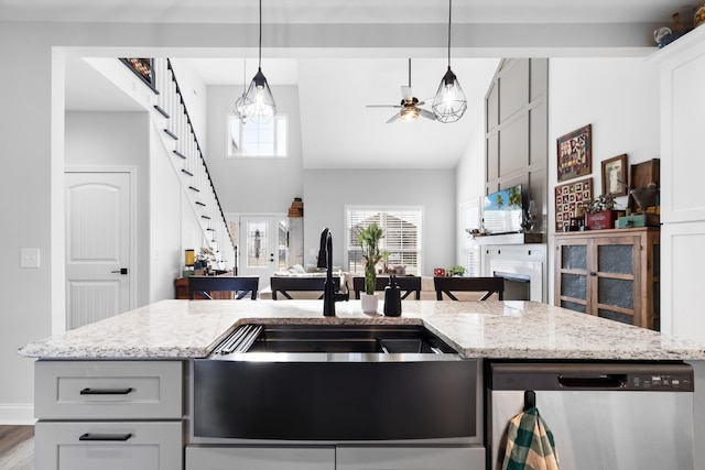 kitchen featuring light stone countertops, decorative light fixtures, ceiling fan, and dishwasher