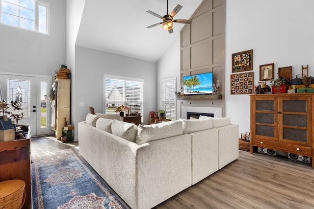 living room with light hardwood / wood-style flooring, high vaulted ceiling, and ceiling fan