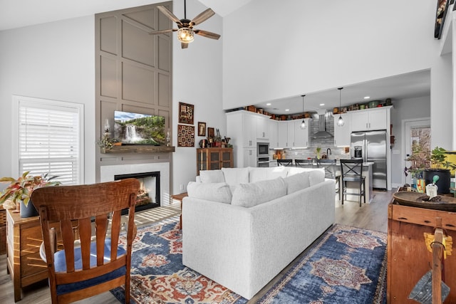 living room featuring ceiling fan, light hardwood / wood-style floors, and high vaulted ceiling