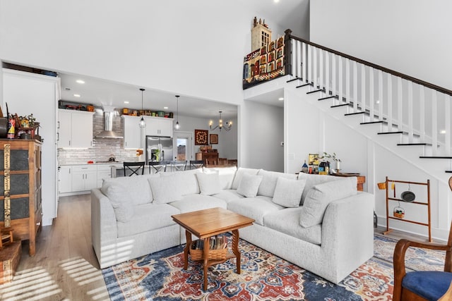 living room featuring a towering ceiling, light hardwood / wood-style floors, and a notable chandelier