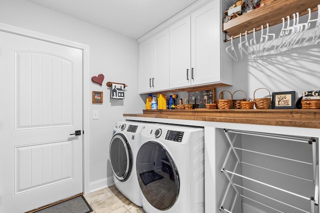 clothes washing area with washer and dryer, cabinets, and light tile patterned floors