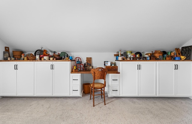 interior space with white cabinets, light carpet, and lofted ceiling