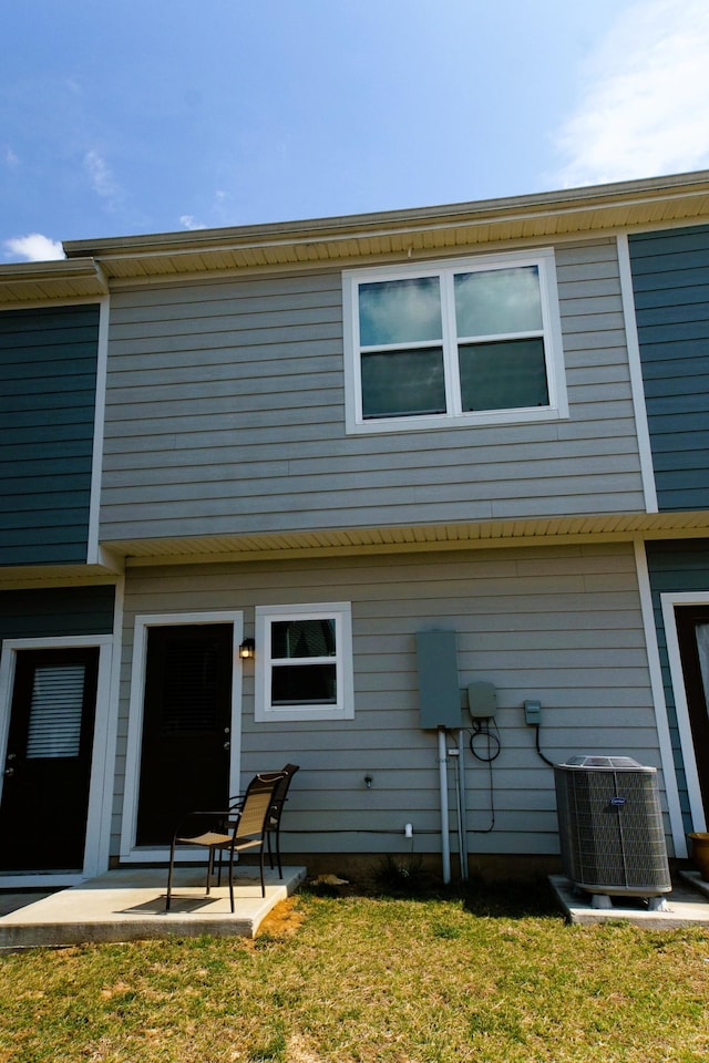 rear view of house featuring a lawn, cooling unit, and a patio