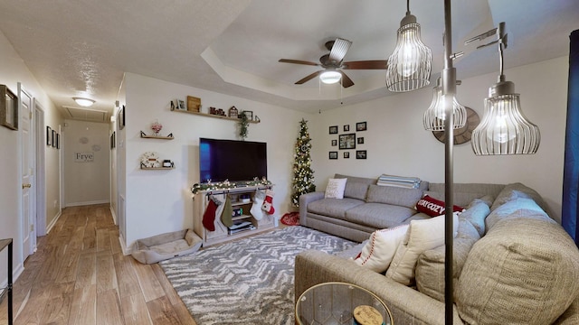 living room featuring hardwood / wood-style floors, ceiling fan, and a tray ceiling