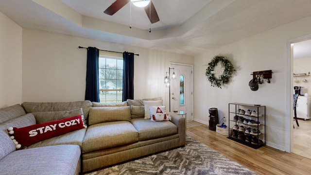 living room featuring a raised ceiling, ceiling fan, and hardwood / wood-style floors