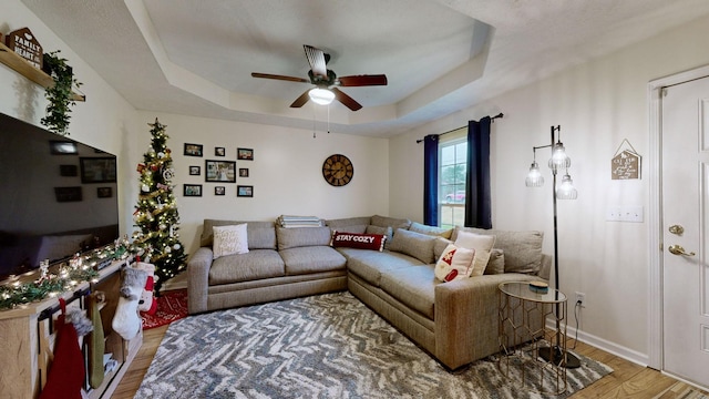 living room with a tray ceiling, ceiling fan, and hardwood / wood-style flooring