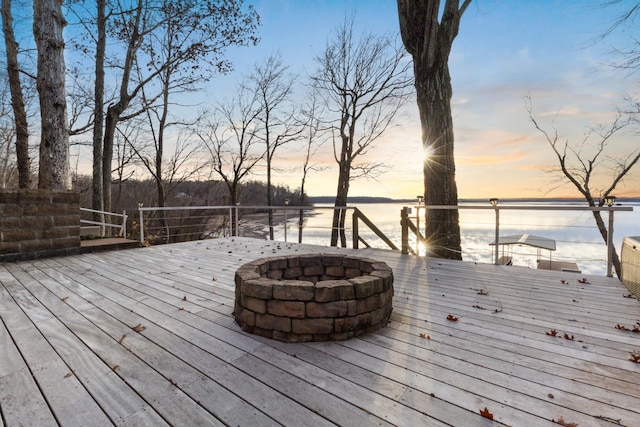 deck at dusk with a water view and an outdoor fire pit