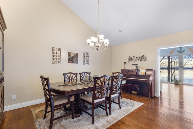 dining space with high vaulted ceiling, hardwood / wood-style flooring, and an inviting chandelier