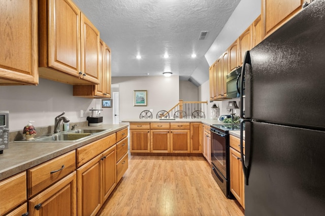 kitchen with sink, black appliances, a textured ceiling, and light hardwood / wood-style flooring