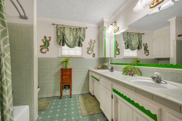 bathroom featuring crown molding, a textured ceiling, shower / tub combo with curtain, vanity, and tile walls