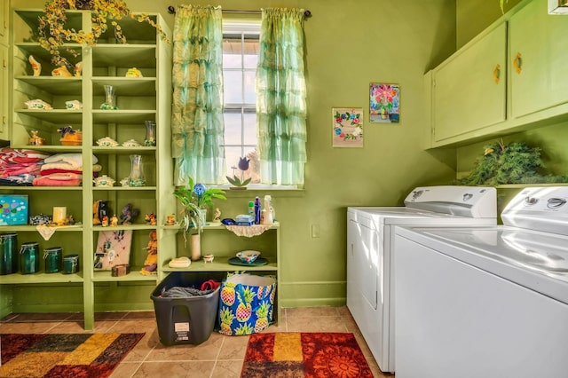 laundry area featuring washing machine and clothes dryer, light tile patterned flooring, and cabinets