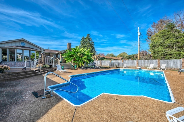 view of swimming pool featuring a sunroom, a diving board, and a patio