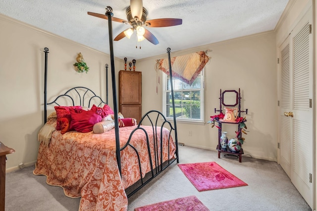 carpeted bedroom with a textured ceiling, a closet, ceiling fan, and crown molding