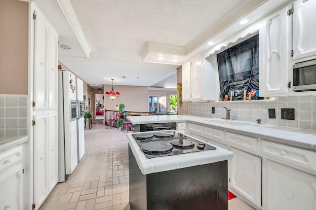 kitchen with a textured ceiling, tasteful backsplash, white cabinetry, and sink