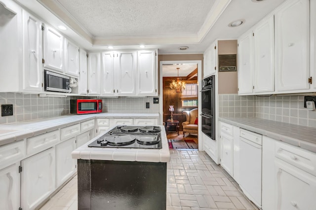 kitchen featuring backsplash, white cabinetry, tile counters, and black appliances