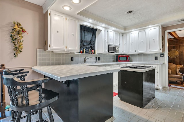 kitchen featuring sink, tile countertops, decorative backsplash, white cabinets, and appliances with stainless steel finishes