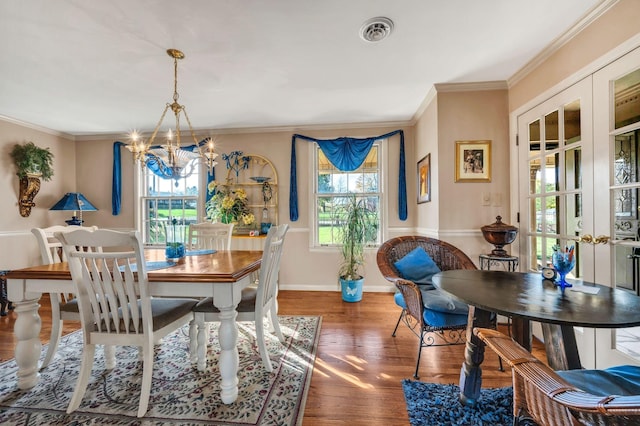 dining space with a chandelier, dark hardwood / wood-style floors, ornamental molding, and french doors