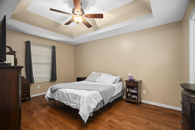 bedroom featuring a raised ceiling, ceiling fan, and dark hardwood / wood-style floors