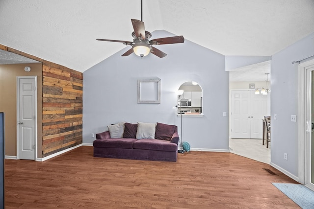 living room with hardwood / wood-style floors, ceiling fan with notable chandelier, lofted ceiling, and a textured ceiling