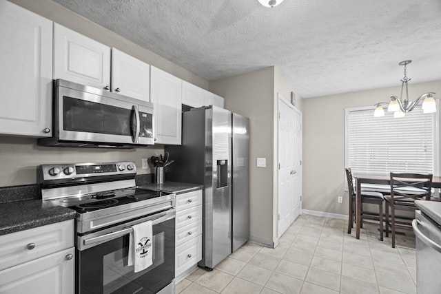 kitchen with pendant lighting, light tile patterned floors, appliances with stainless steel finishes, a notable chandelier, and white cabinetry