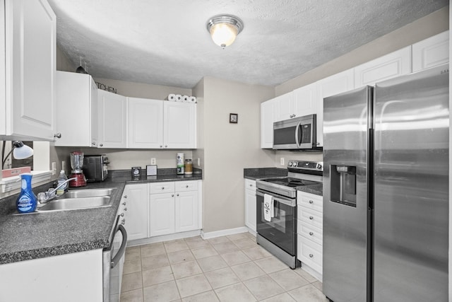 kitchen featuring white cabinetry, sink, light tile patterned floors, and appliances with stainless steel finishes