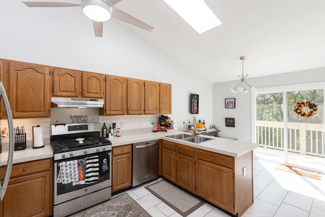 kitchen with kitchen peninsula, appliances with stainless steel finishes, backsplash, sink, and decorative light fixtures