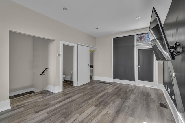 unfurnished bedroom with connected bathroom and wood-type flooring