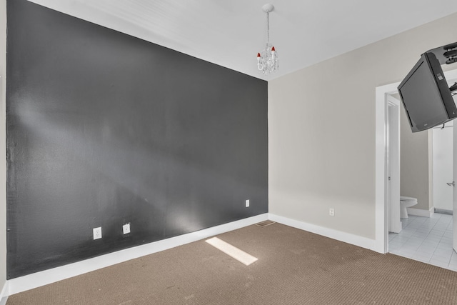 empty room featuring light carpet and an inviting chandelier