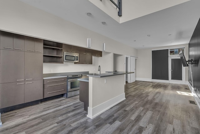 kitchen featuring appliances with stainless steel finishes, dark hardwood / wood-style floors, a breakfast bar area, and an island with sink