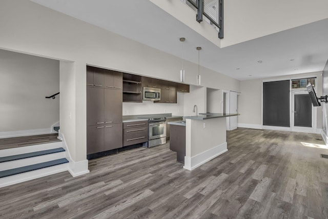 kitchen with a center island with sink, dark hardwood / wood-style floors, stainless steel appliances, and decorative light fixtures