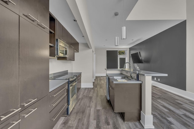 kitchen with dark wood-type flooring, sink, stainless steel appliances, and decorative light fixtures