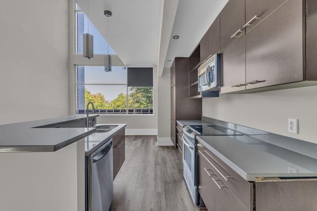 kitchen with sink, stainless steel appliances, decorative light fixtures, and hardwood / wood-style flooring