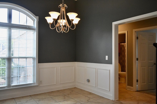 spare room featuring light tile patterned floors, an inviting chandelier, and a healthy amount of sunlight