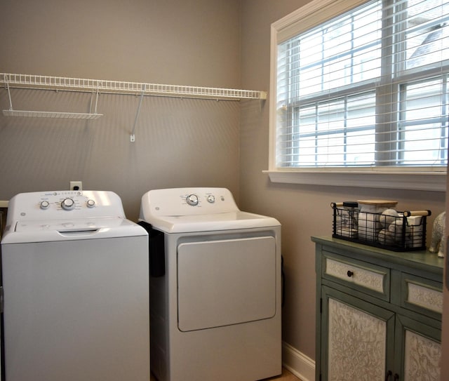 clothes washing area featuring separate washer and dryer and cabinets