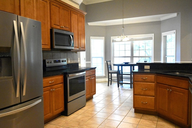 kitchen with stainless steel appliances, a wealth of natural light, a notable chandelier, and light tile patterned flooring