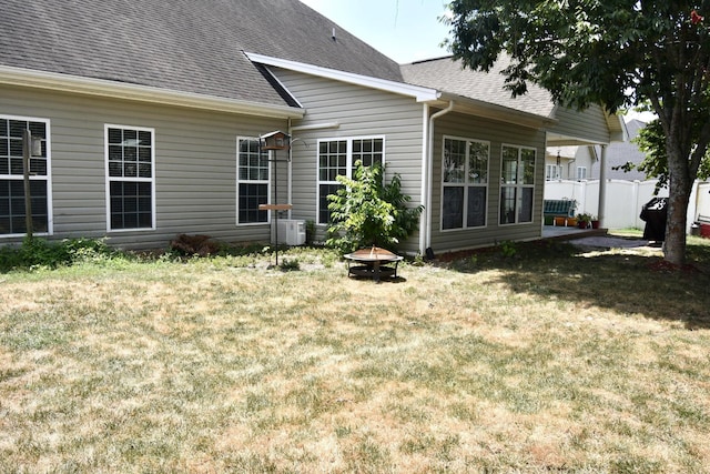 rear view of property with a yard and a fire pit