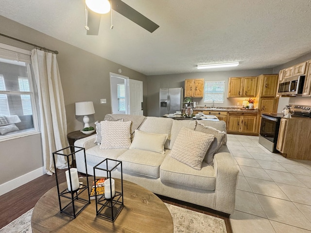 living room with a wealth of natural light, ceiling fan, light tile patterned flooring, and a textured ceiling