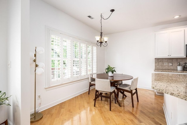 dining space with light wood-type flooring and an inviting chandelier