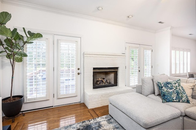 living room featuring hardwood / wood-style floors, ornamental molding, and a brick fireplace