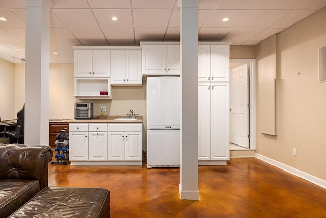 kitchen featuring white refrigerator, white cabinetry, and sink