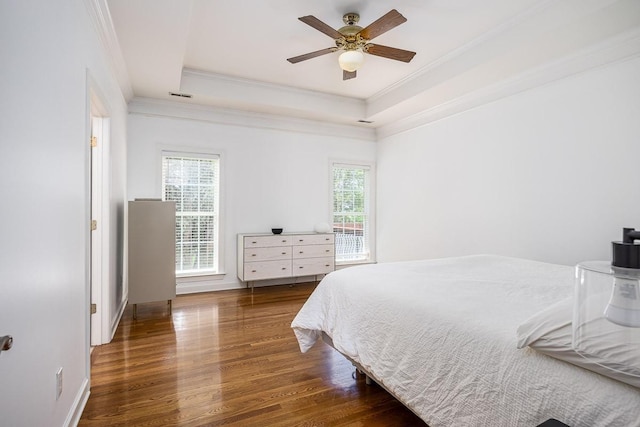 bedroom with a raised ceiling, ceiling fan, dark wood-type flooring, and crown molding