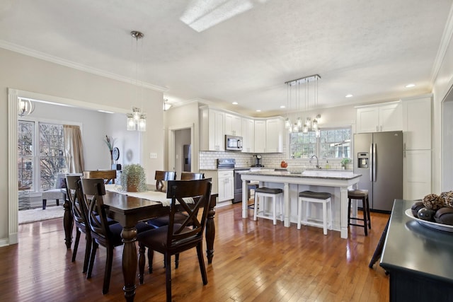 dining area with dark wood-type flooring, ornamental molding, and sink