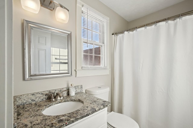 bathroom with toilet, vanity, and curtained shower