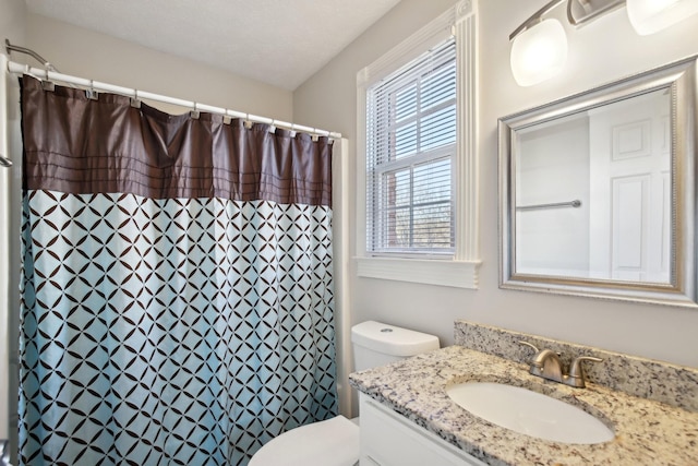 bathroom featuring toilet, vanity, plenty of natural light, and walk in shower