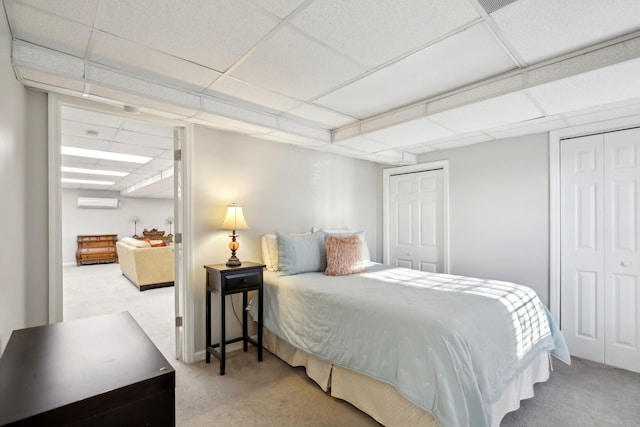 carpeted bedroom featuring a paneled ceiling and multiple closets